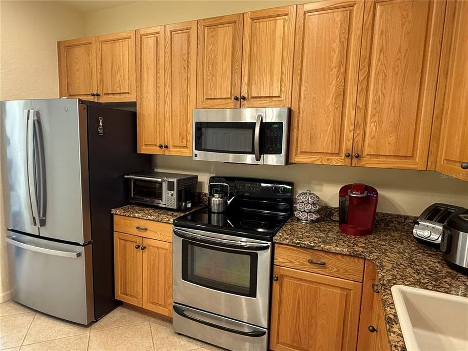 Kitchen features wood cabinets, granite counters, stainless appliances and new fridge