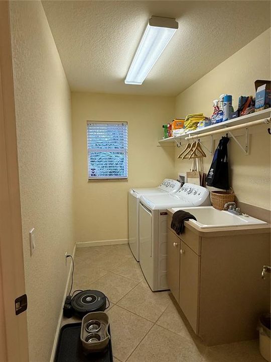 Laundry features wash sink, solid shelving and additional broom closet