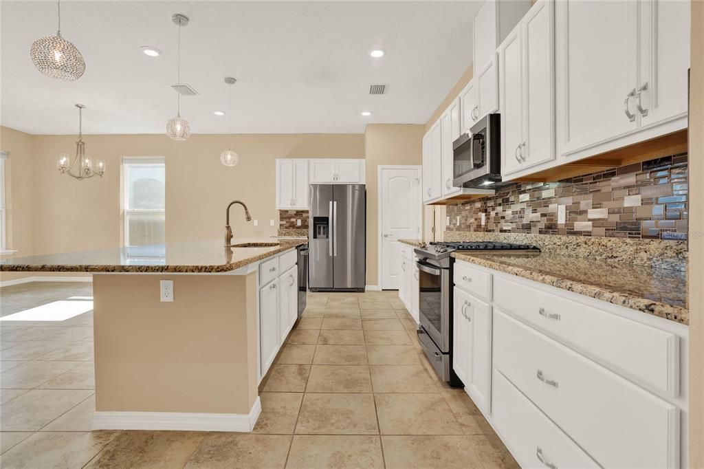 CHEF'S KITCHEN WITH EXPANSIVE ISLAND FOR ADDED SEATING & PENDANT LIGHTING, STAINLESS STEEL APPLIANCES, PANTRY CLOSET, GAS COOKING (CAN SWITCH TO ELECTRIC IF PREFERRED), STYLISH BACKSPLACH, AND