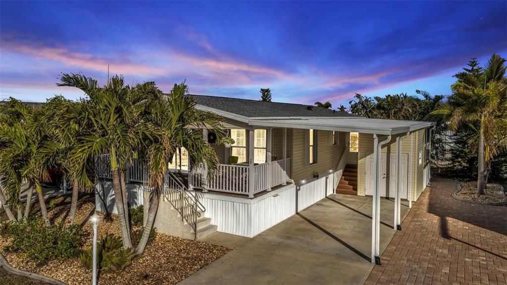 Front dusk shot- extra long, pavered parking on right of carport