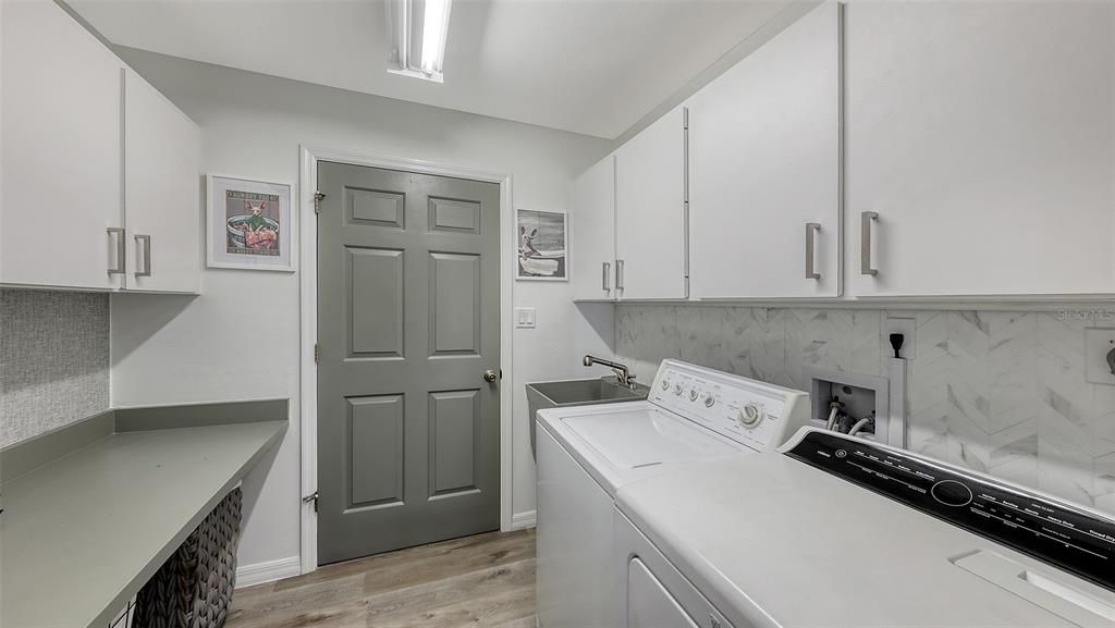 In-Home laundry with laundry sink, new plumbing fixtures, ample storage space and folding area.