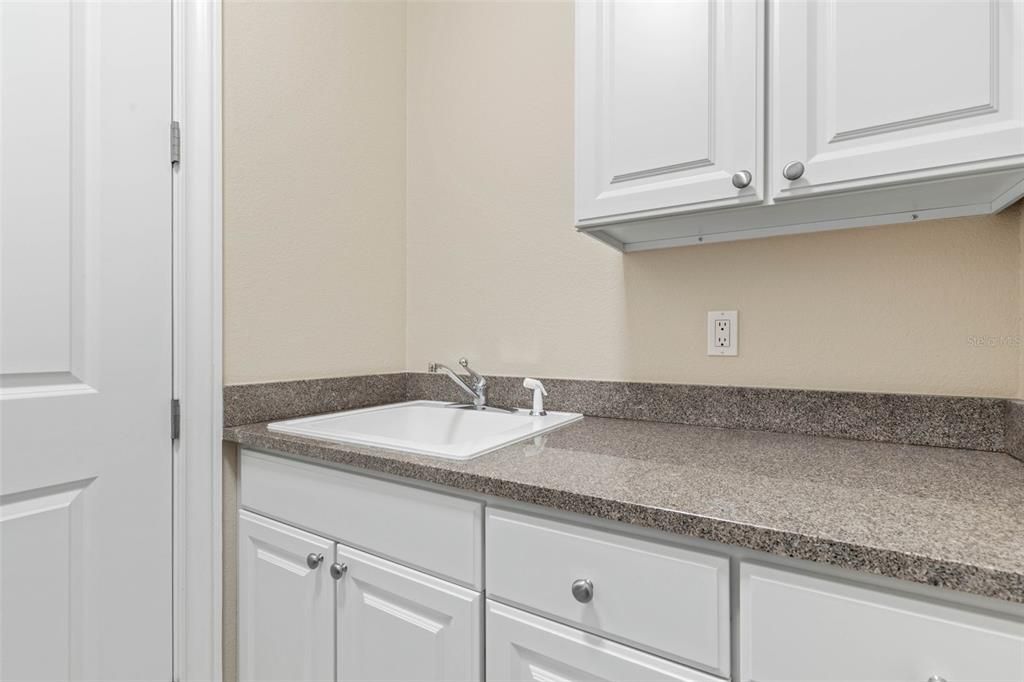 Lots of cabinets with granite tops, and a sink in utility