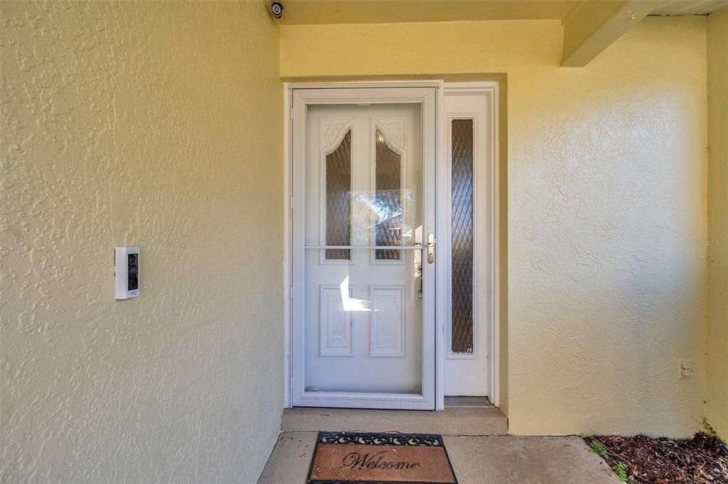 Front door with storm door. Ring doorbell and security cameras stay.