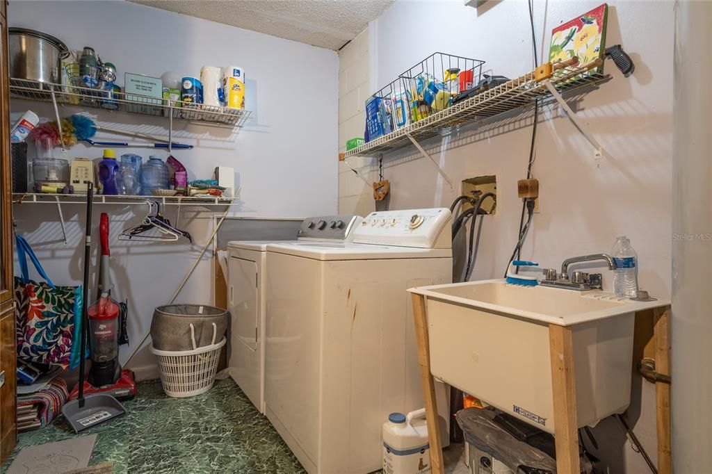 Indoor utility room includes shelving, washer, dryer and utility sink.