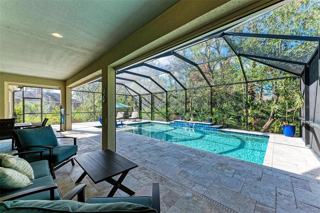 Large covered travertine lanai with tons of seating space.