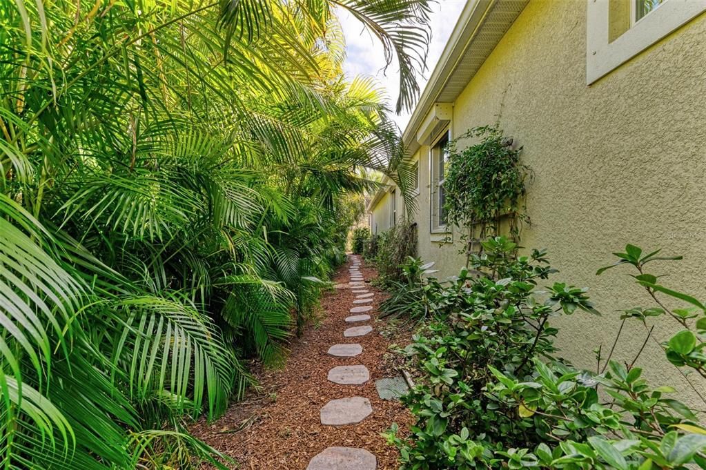 Walking path along side of house through lush landscaping.