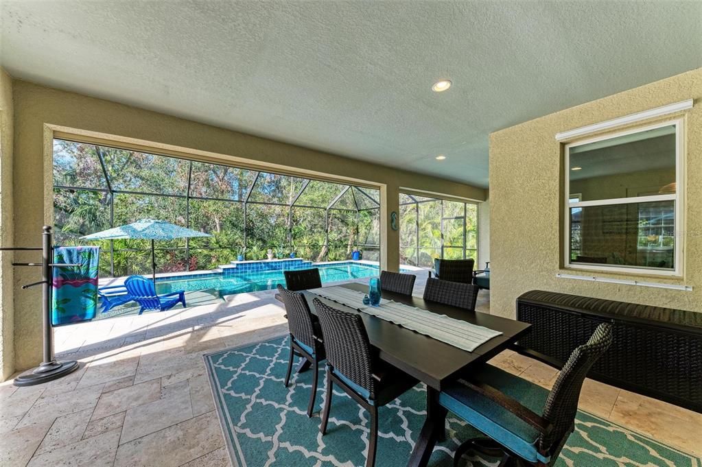 Large covered travertine lanai with tons of seating space.