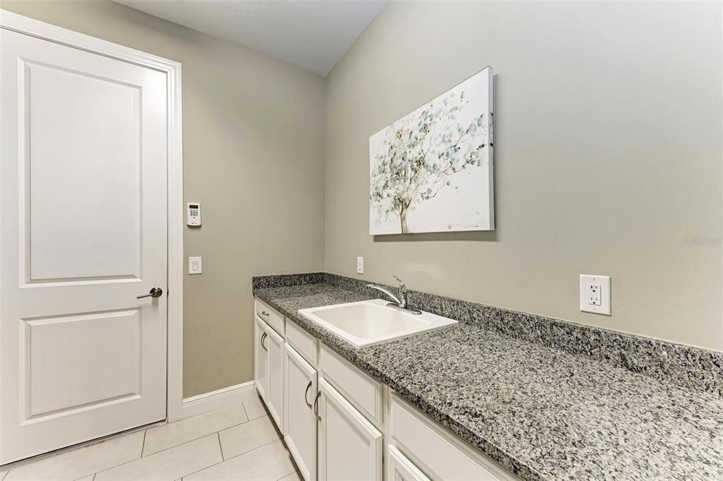 Sink, counter space and cabinetry in the laundry room.