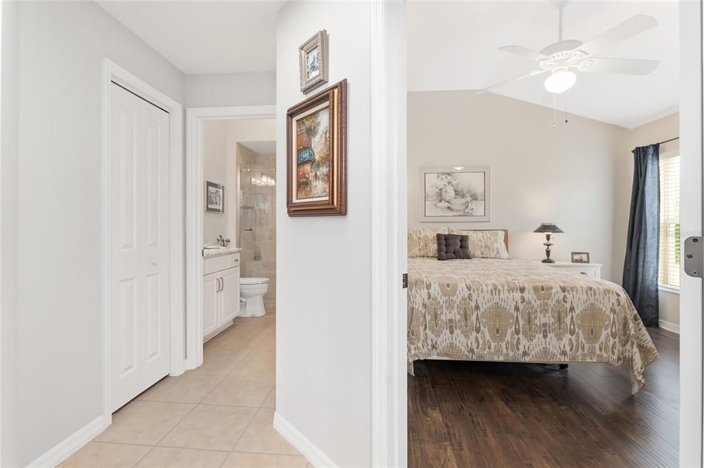 View of BEDROOM #3 (R) - Shows VAULTED CEILING, ceiling fan with light, and handsome WOOD LAMINATE FLOORS. BATHROOM 2 is located down the HALLWAY (L).