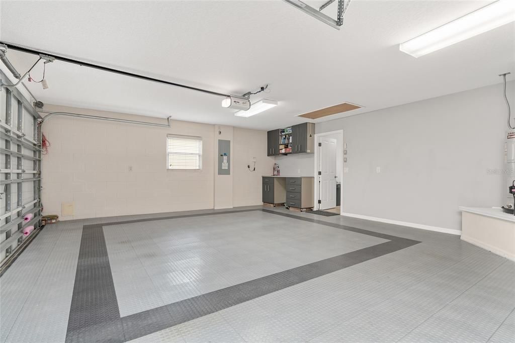 View of 2.5 CAR GARAGE - Shows premium interlocking garage floor tiles. Doorway (back center) leads to versatile OFFICE/INTERIOR LAUNDRY ROOM