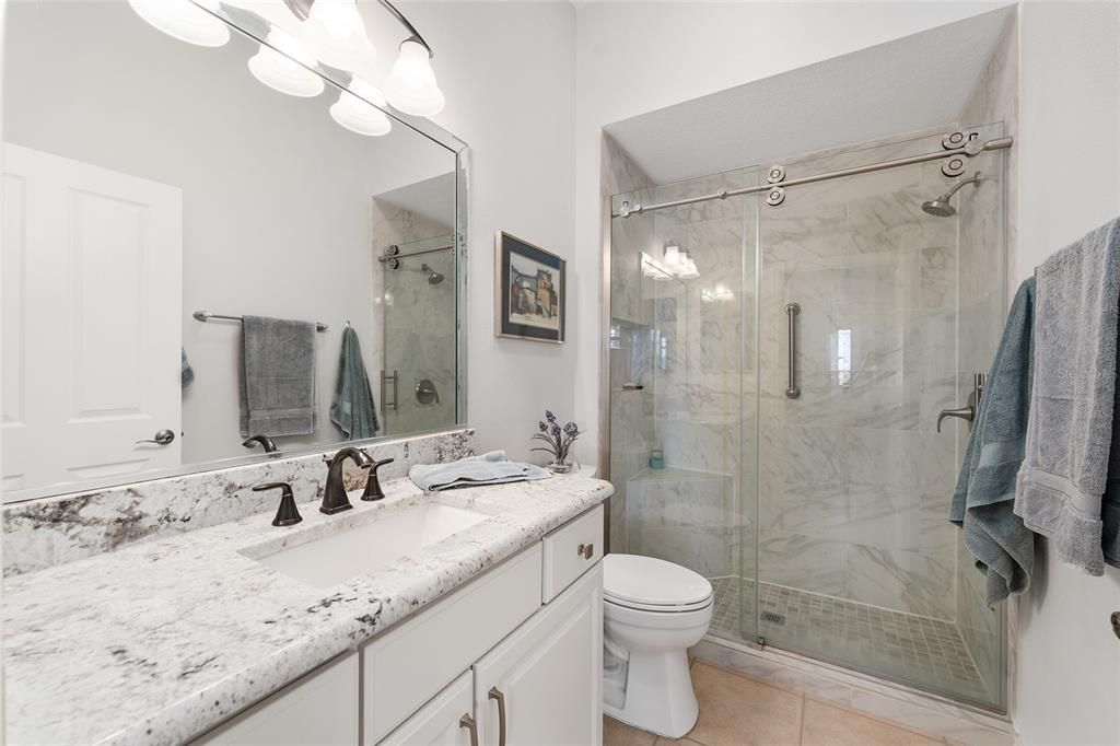 View of BATHROOM #2 - Shows upgraded features of matching GRANITE COUNTERTOP, COMFORT HEIGHT TOILET, and tiled SHOWER with FRAMELESS GLASS DOOR (2019).