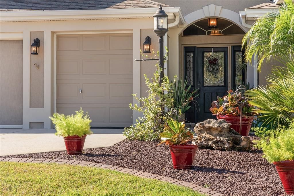 FRONT EXTERIOR - Close up of well maintained landscaping and the inviting COVERED FRONT PORCH. Note the lovely HALF LITE front door & matching side lite panels w/ glass & wrought iron design