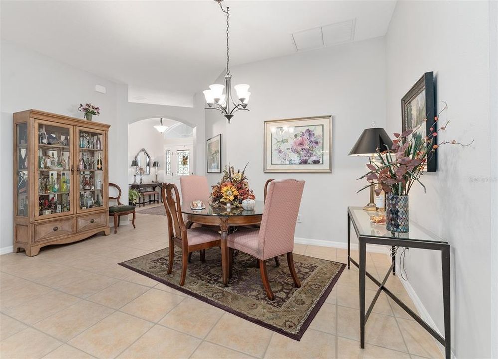 View of DINING ROOM - Shows large TILED FLOORING, ~ 10' ceiling in Dining Room (front center) and decorative arch defining the ANGLED FOYER space (back center).