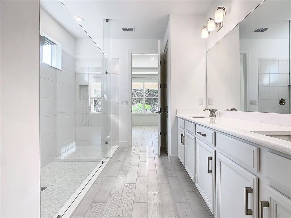 Main Bath with Double Sinks, Linen Closet and Frameless Shower.