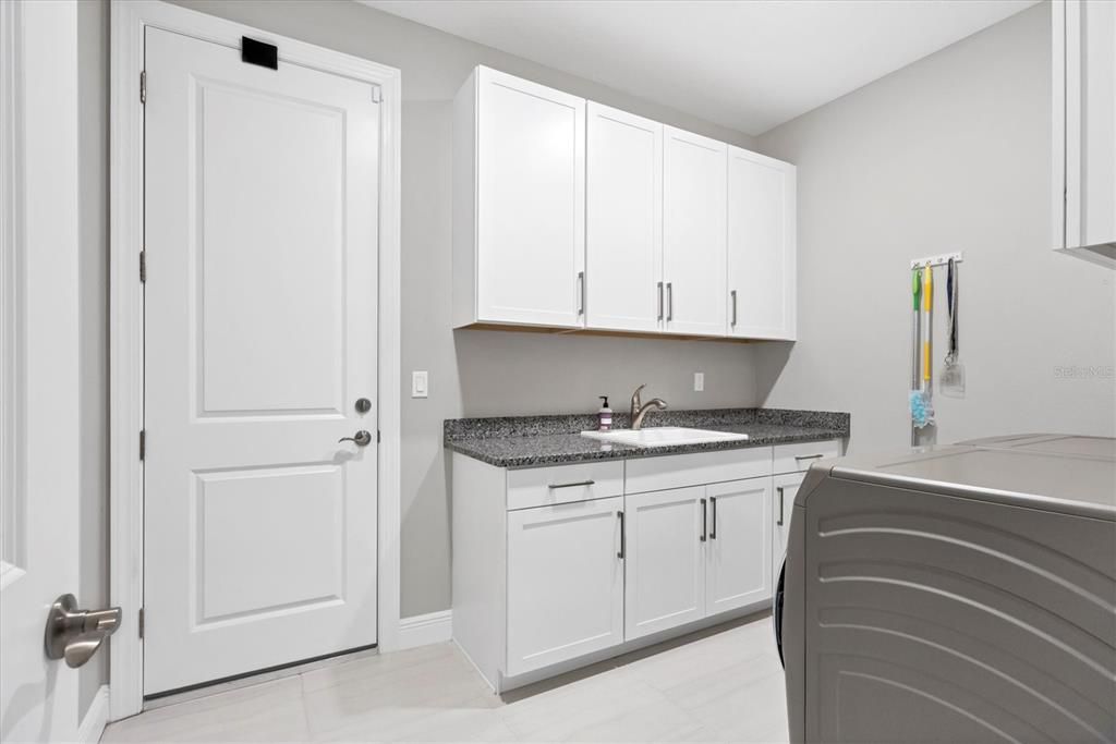 Laundry room with GE washer and dryer, upper and lower cabinets and utility sink