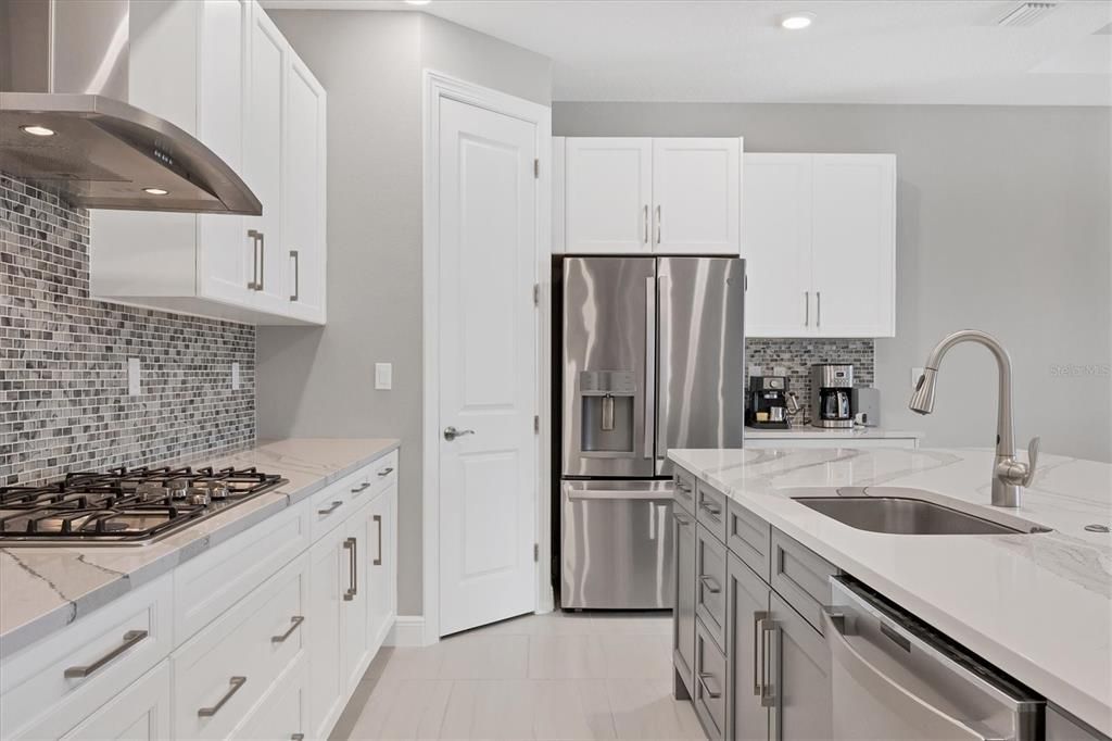 Kitchen offers lovely glass backsplash tiling and a huge pantry with custom wood shelving