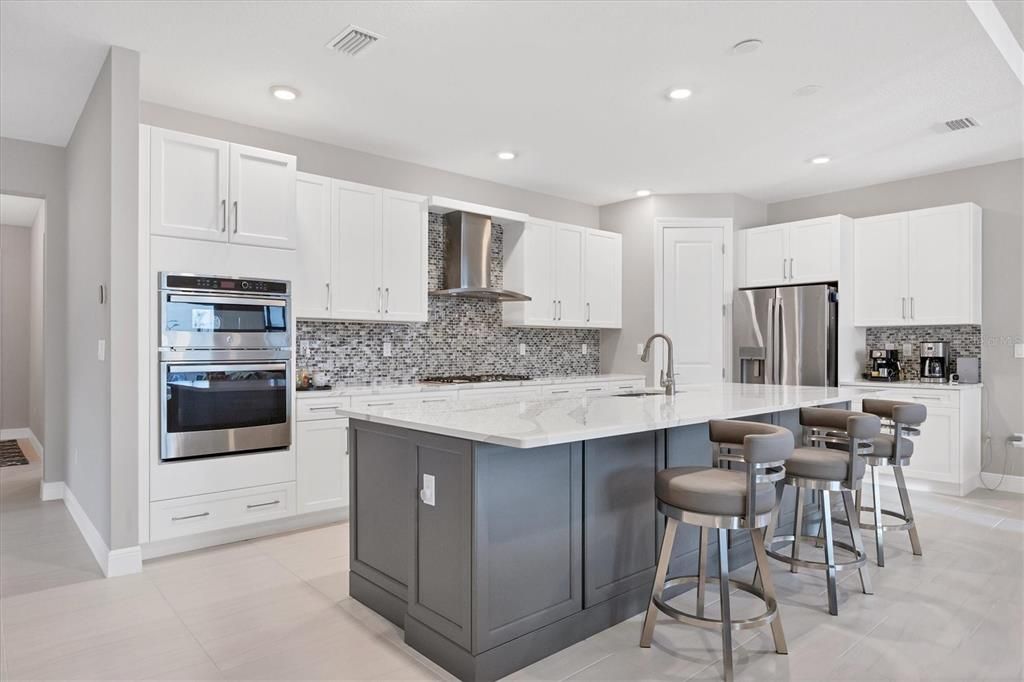 gourmet kitchen with upgraded appliances, backsplash to top of cabinets, Cambria quartz countertops,