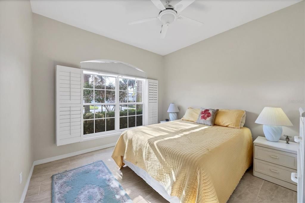 Bright and light guest bedroom. Plantation shutters on a large window.