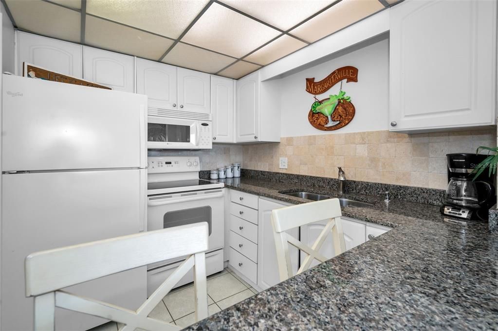 Light & Bright Kitchen with Granite Surfaces, Breakfast Bar and White Appliances.