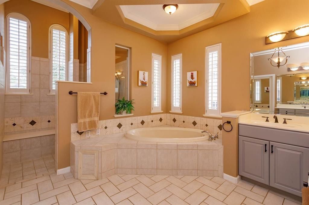 Primary bathroom with two vanities, large shower, private commode and jetted tub