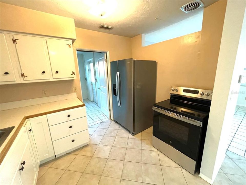 Kitchen with tile counters, new lower cabinets, refrigerator and dishwasher