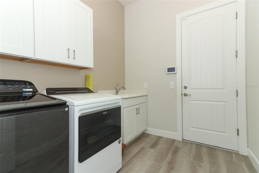 Indoor Laundry room with machines, cabinets and sink.