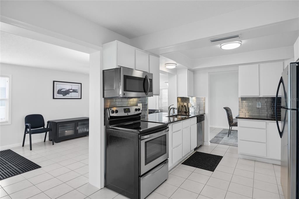 This updated Kitchen has beautiful granite counters and stainless steel appliances that have barely been used!  This view also shows the Family Room at the back of the home.