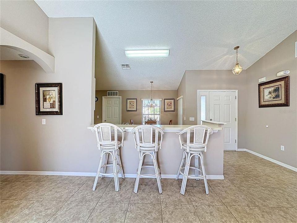 Looking toward the front of the home, you will notice the breakfast bar and front entryway.