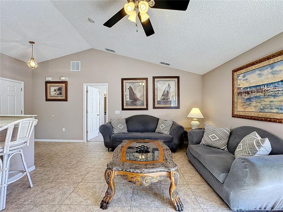 The living room has vaulted ceilings and a ceiling fan.