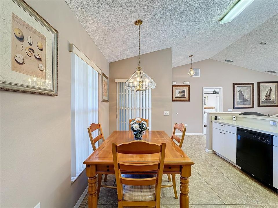 The dining area in the kitchen looking toward the front entry and the primary bedroom is past the entry.