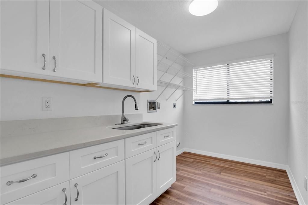 Inside Laundry with cabinets, sink and counter