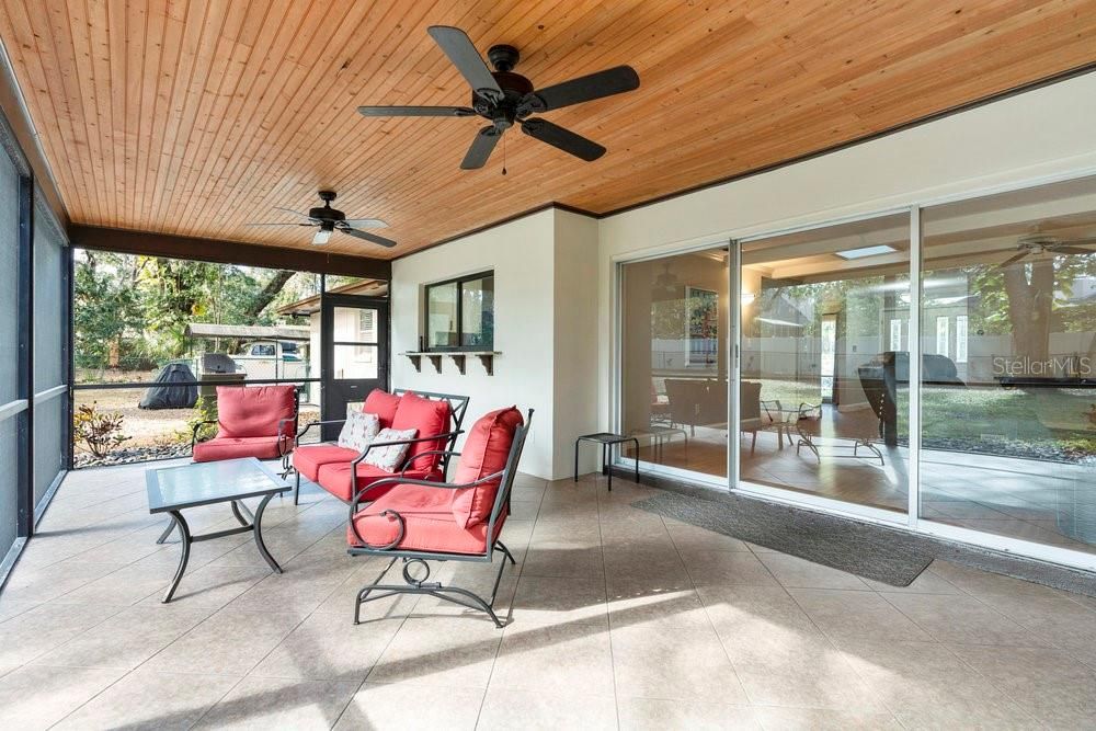 Back porch located off of the Living Room through the telescoping sliding doors, complete with tile flooring, NEW screens, and gorgeous wood accent ceiings