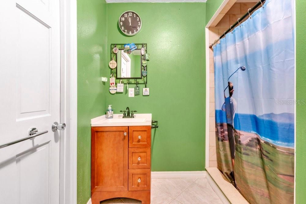 Garage bathroom with walk-in shower, toilet, and sink vanity