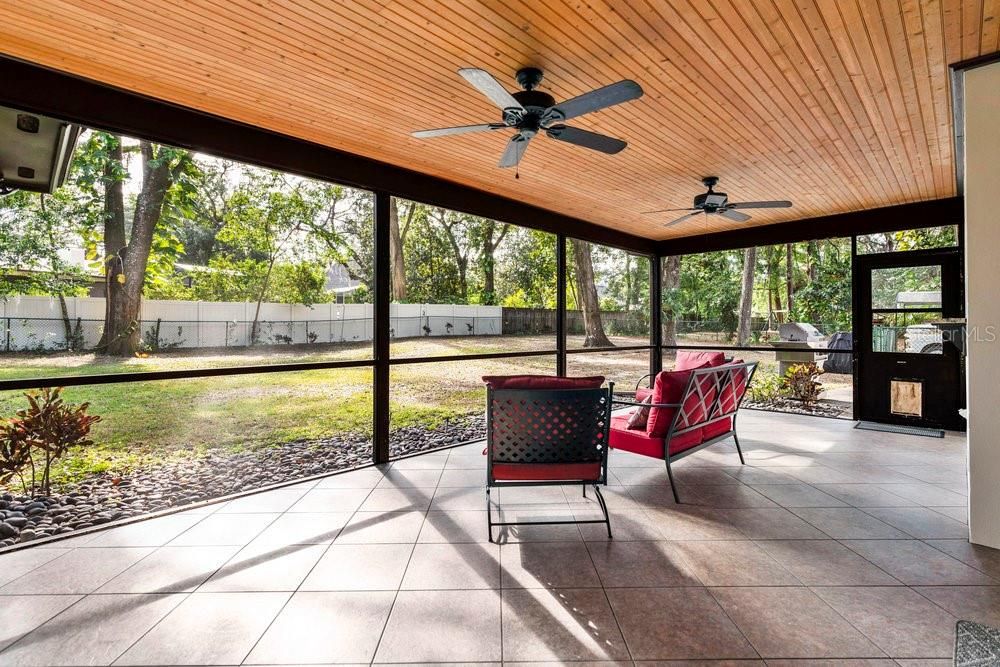 Back porch overlooking the huge backyard and complete with tile flooring, NEW screens, and gorgeous wood accent ceiings