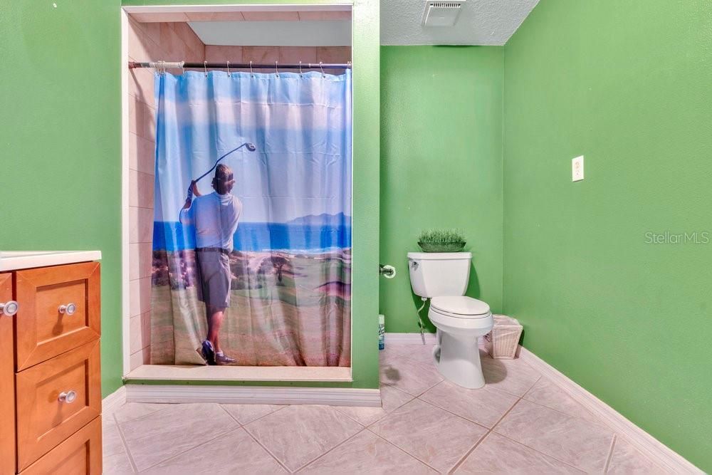 Garage bathroom with walk-in shower, toilet, and sink vanity