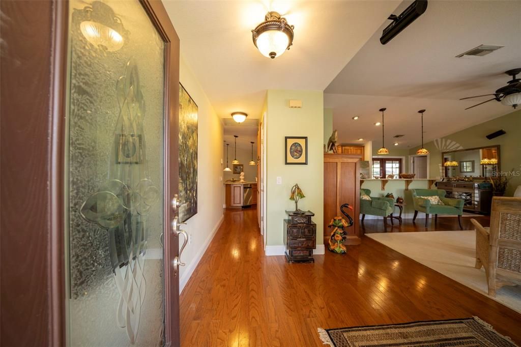 Entrance to home with oak wood floors, living room to right,