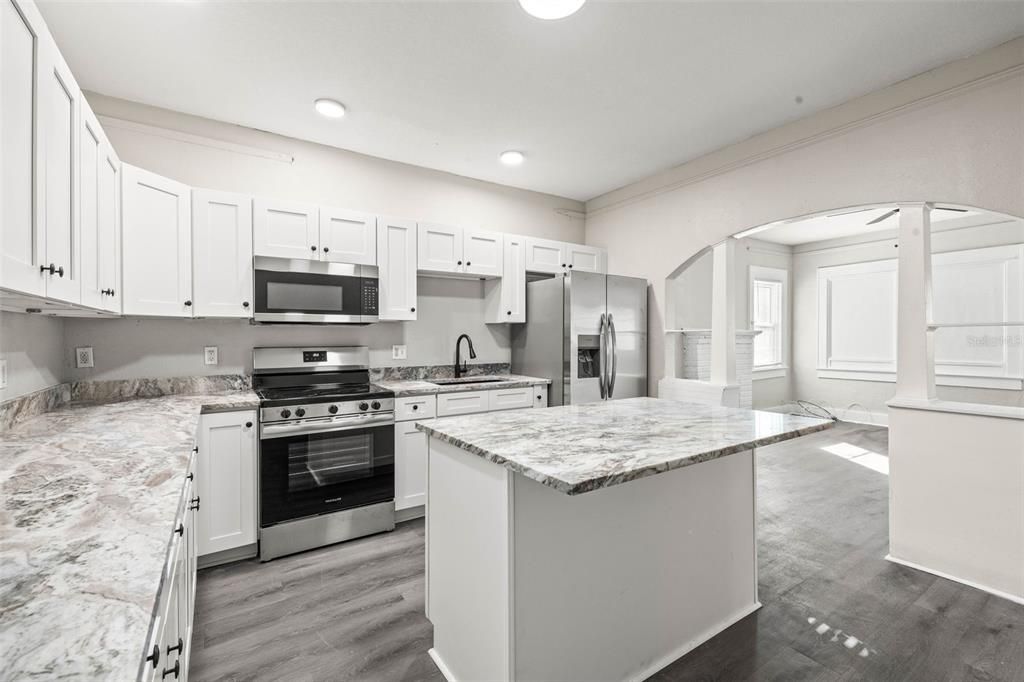 Kitchen with white shaker cabinets, new appliances, Center Island, and stainless steel sink