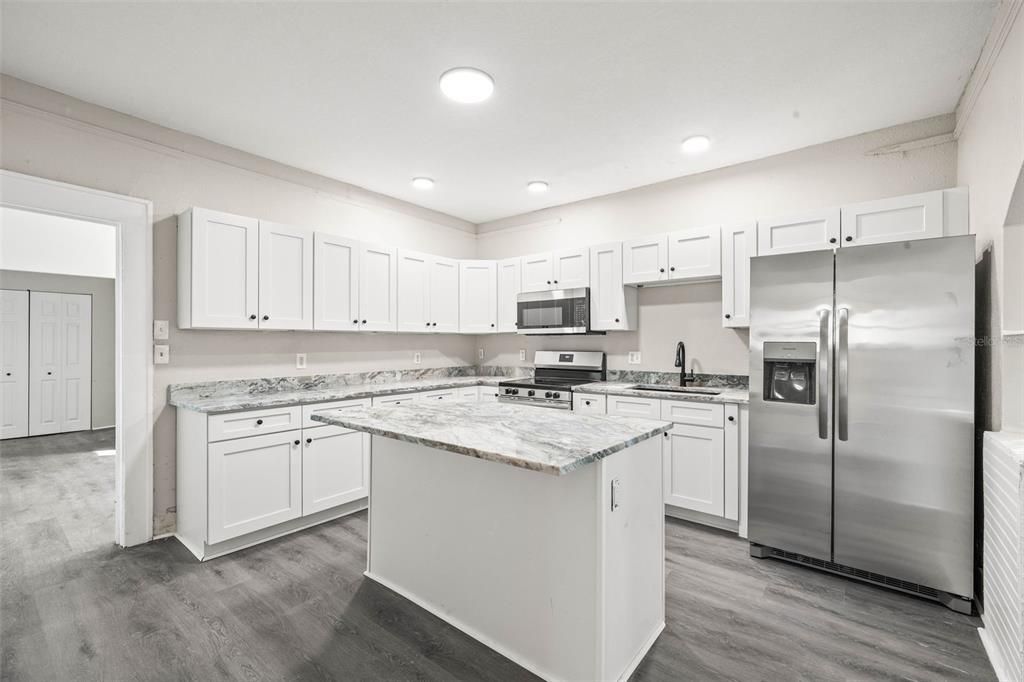 Kitchen with white shaker cabinets, new appliances, Center Island, and stainless steel sink