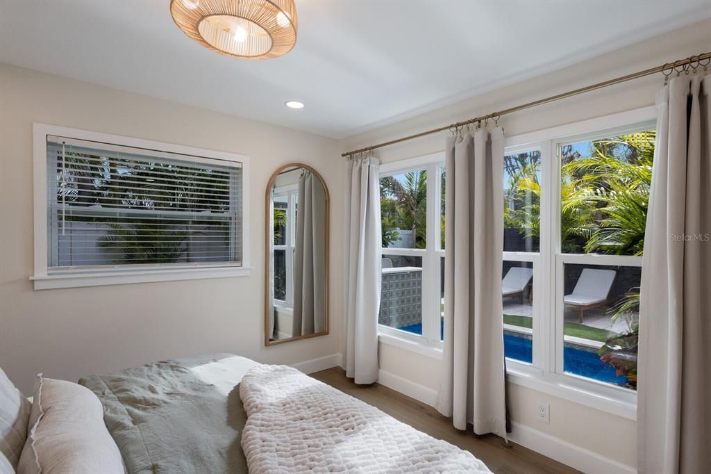 Impact large windows overlooking the tropical backyard from the primary bedroom