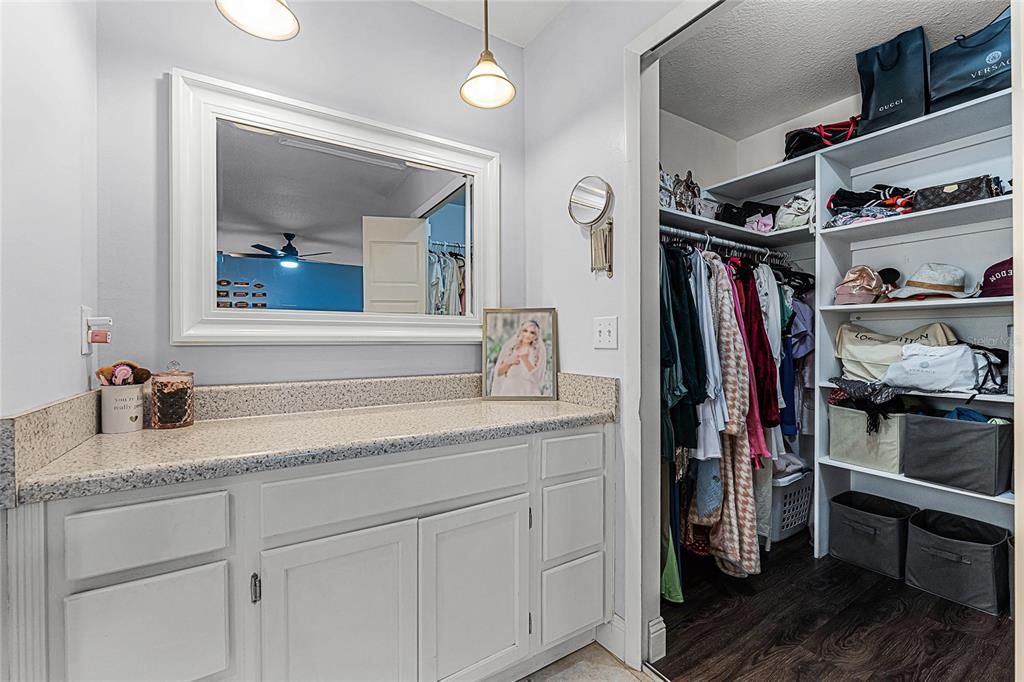 Primary vanity area with access to walk-in closet