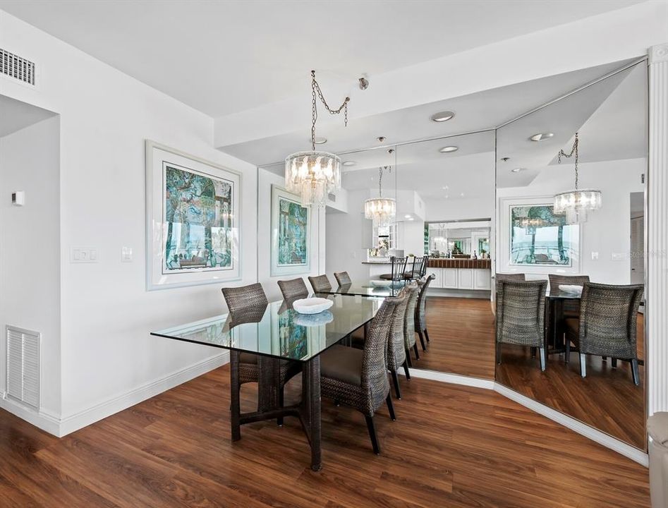 The simple, yet elegant dining room offers recessed lighting in addition to a chandelier, with the mirrored wall expanding this space to feel more spacious.