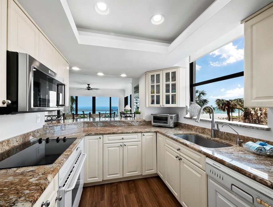 Bright and light, this kitchen offers views of the Gulf through the great room and kitchen window. Tray ceilings with recessed lighting, granite countertops, stainless steel microwave, refrigerator, and a deep single basin deep sink are a few delightful features in the culinary space.