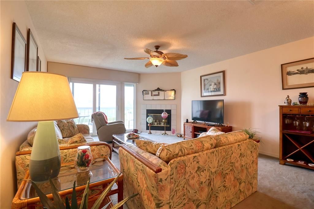 Living room with fireplace and balcony overlooking the tennis courts