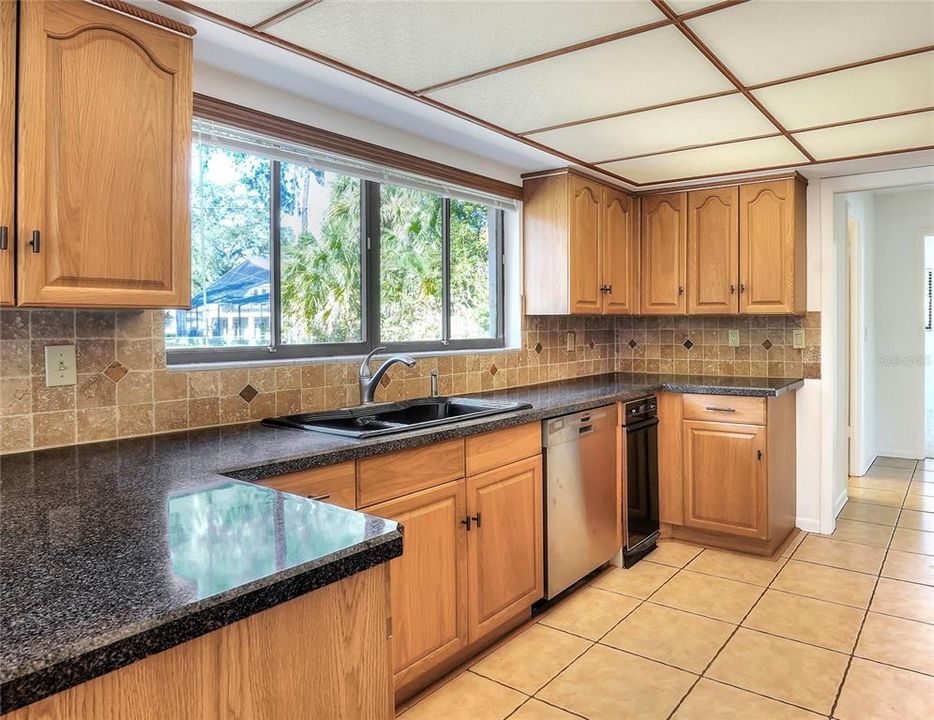 Enjoy the real wood cabinets, long runs of counter for meal prep, baking, and serving, and a double window over the sink in this functional kitchen