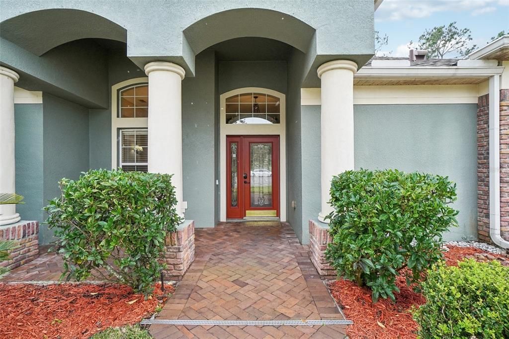 Grand front covered entrance with paved walkway and stone accents