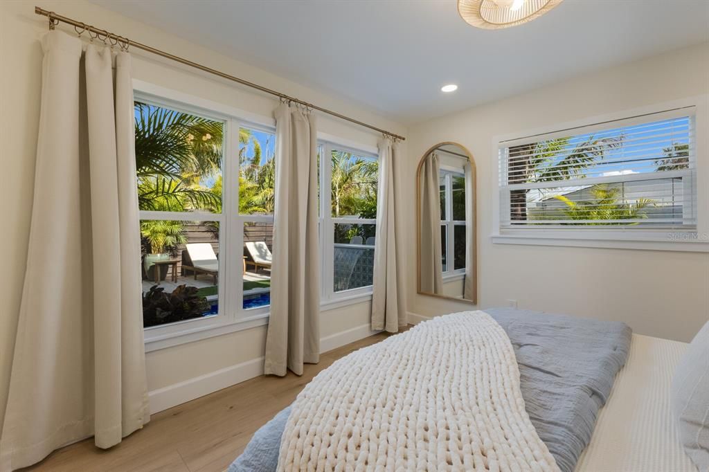 Large windows in primary bedroom overlooking the resort style pool