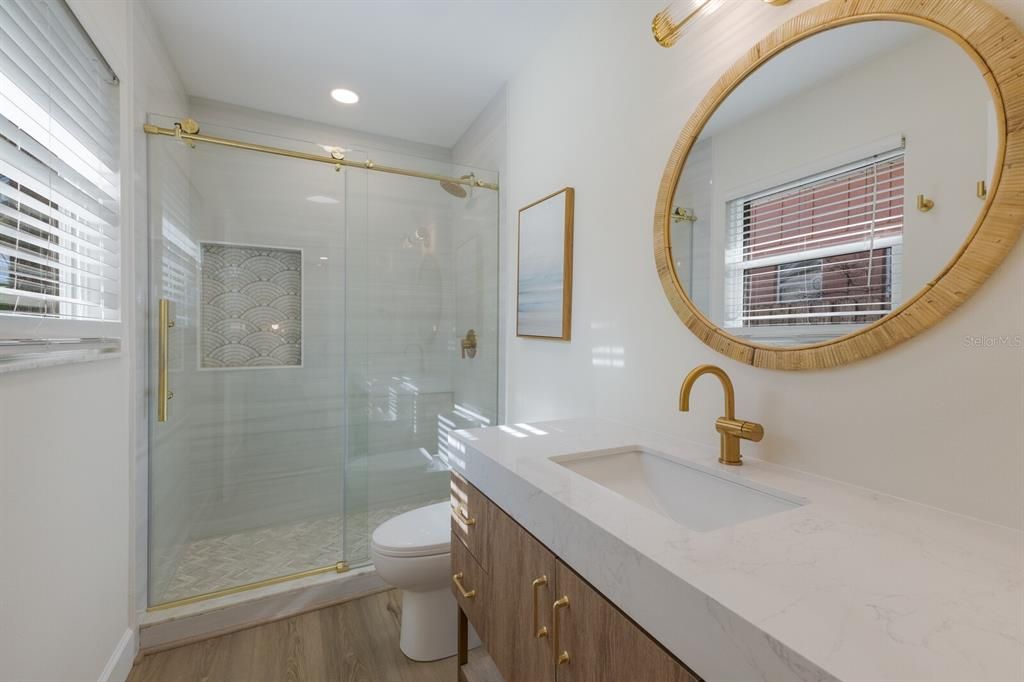 Primary en suite bathroom w/ quartz counters and glassed-in porcelain tile shower