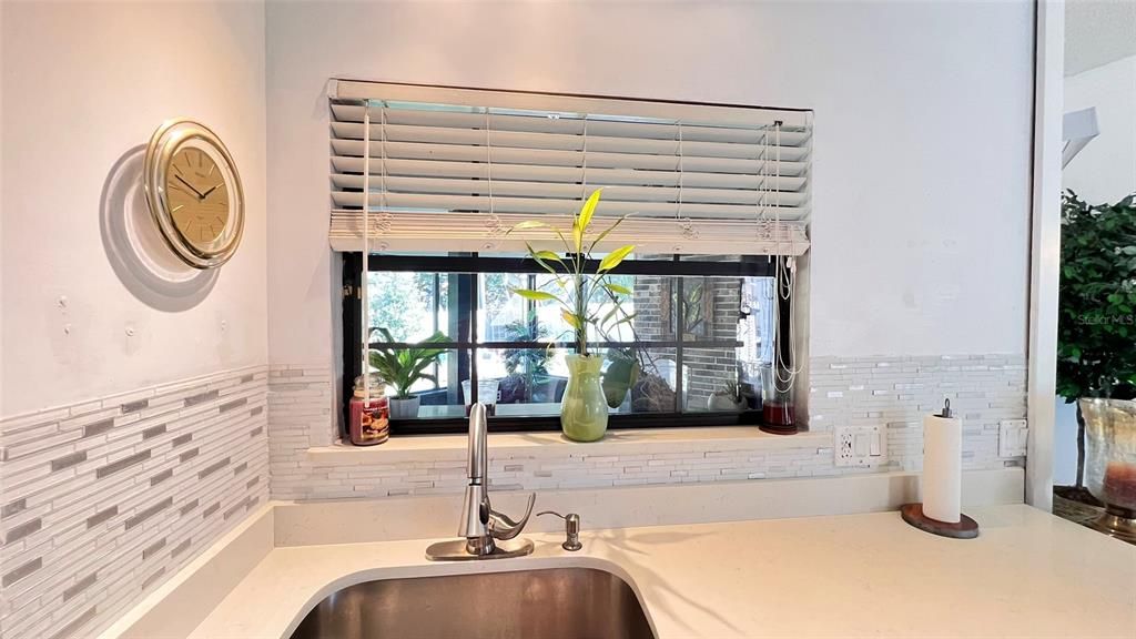 Kitchen with glass back splash, industrial style sink and quartz countertop