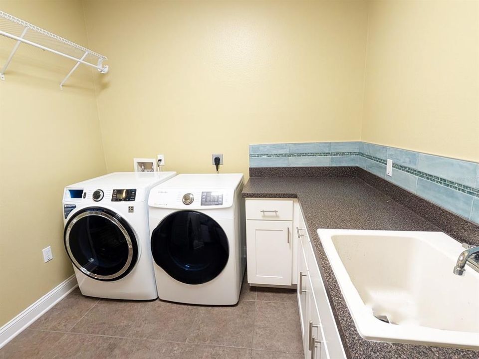 Laundry room with large countertop, sink, cabinet storage and storage closet