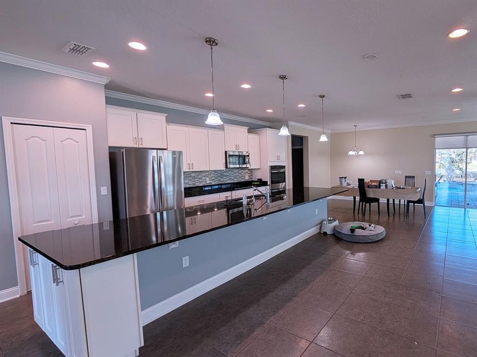 extra long granite kitchen island overlooking the great room, dinette and 4 door sliders leading to outdoor pool area.